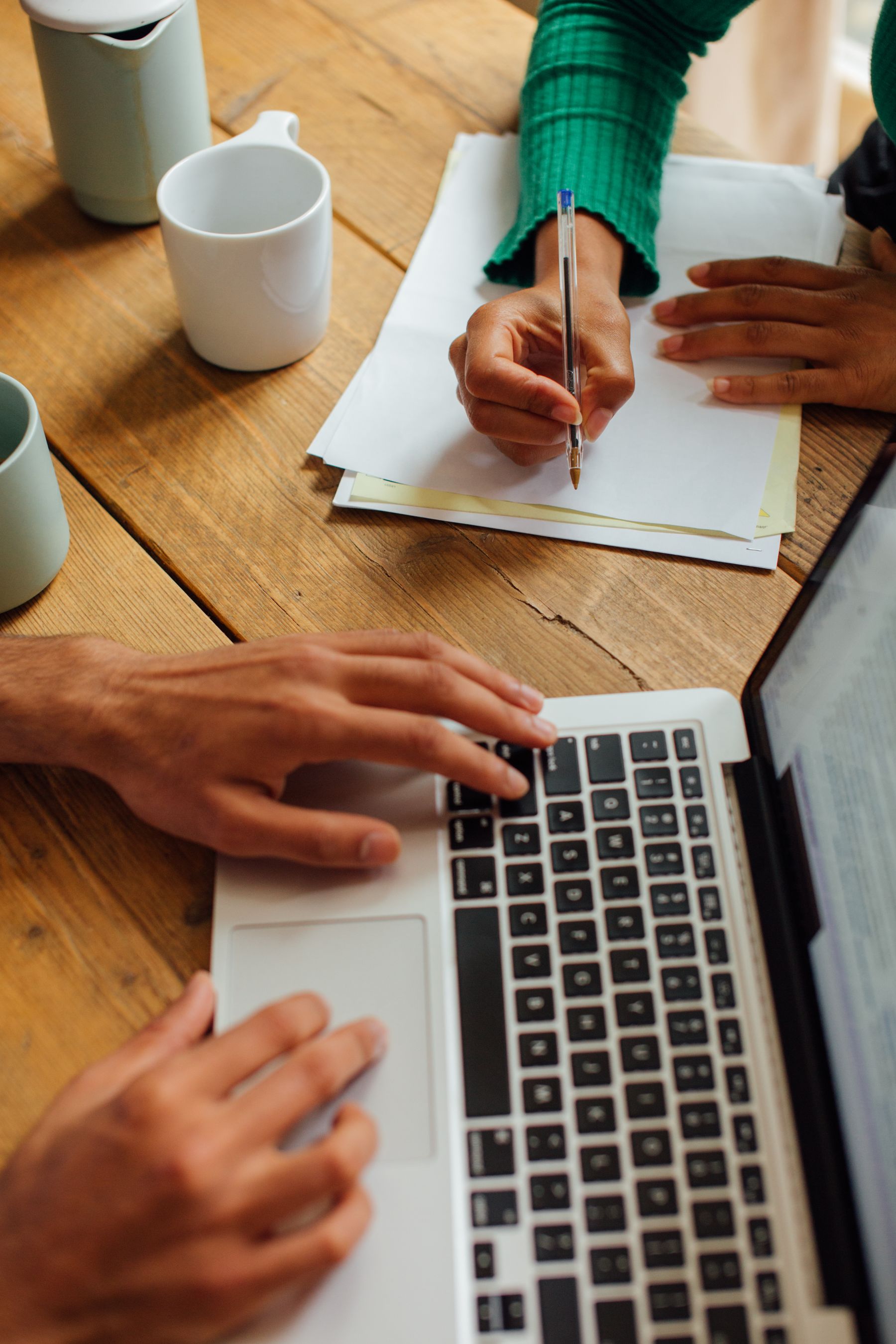 People collaborating with a laptop and taking notes during a website consultation